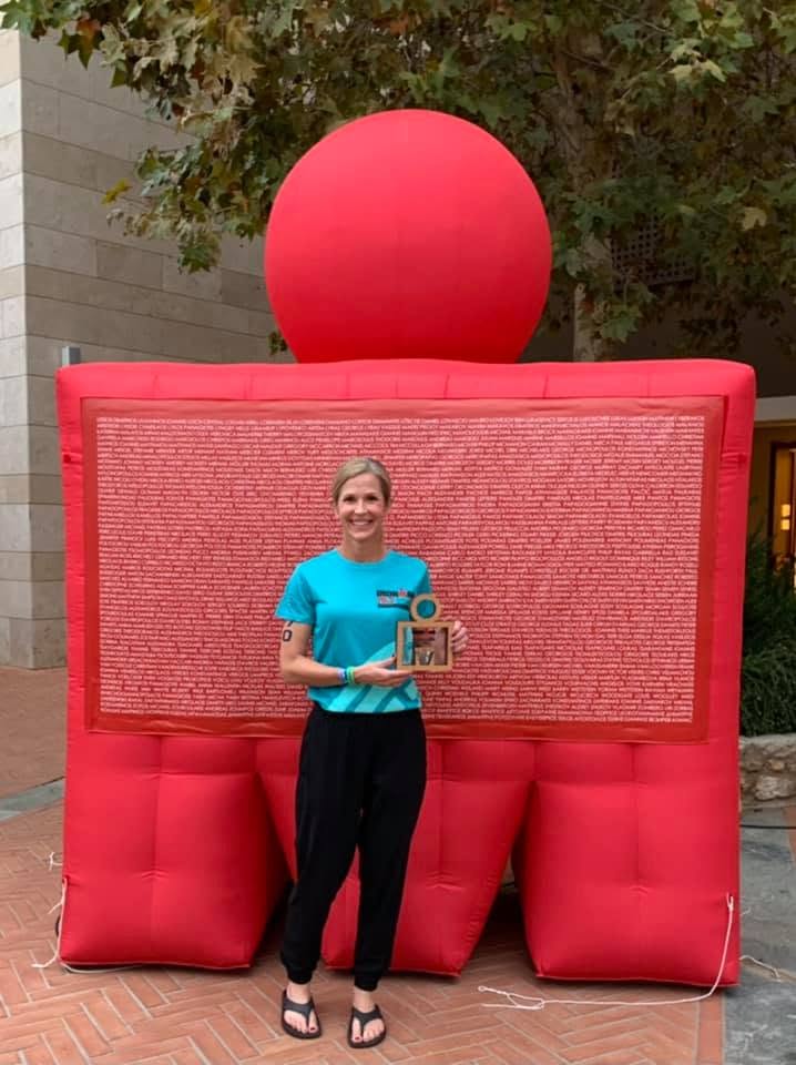 Carrie holding her award in front of a race arch