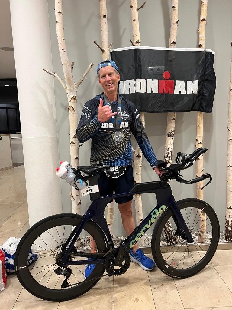 Dale with his triathlon bike in front of an IRONMAN banner
