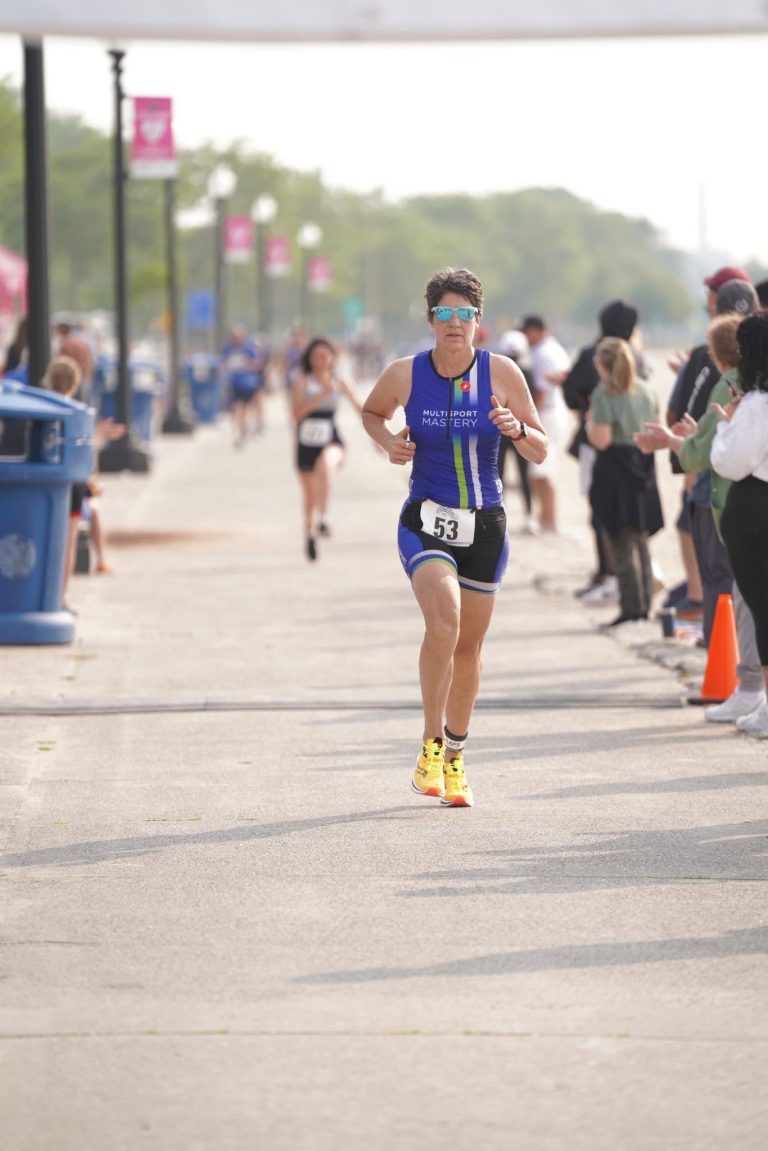 Kathryn running toward the finish line in a Multisport Mastery race kit