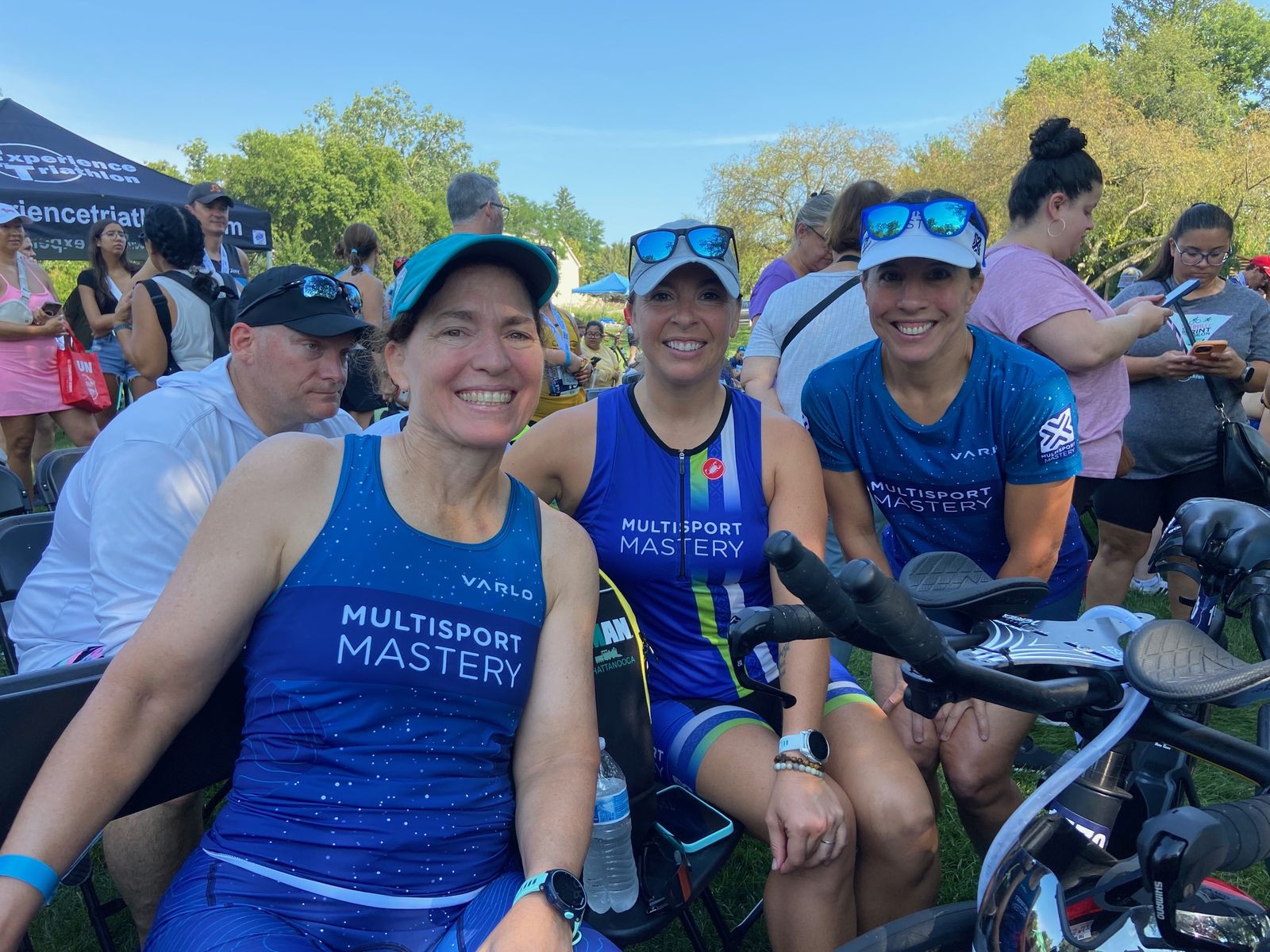 Three Multisport Mastery athletes smiling together after a triathlon
