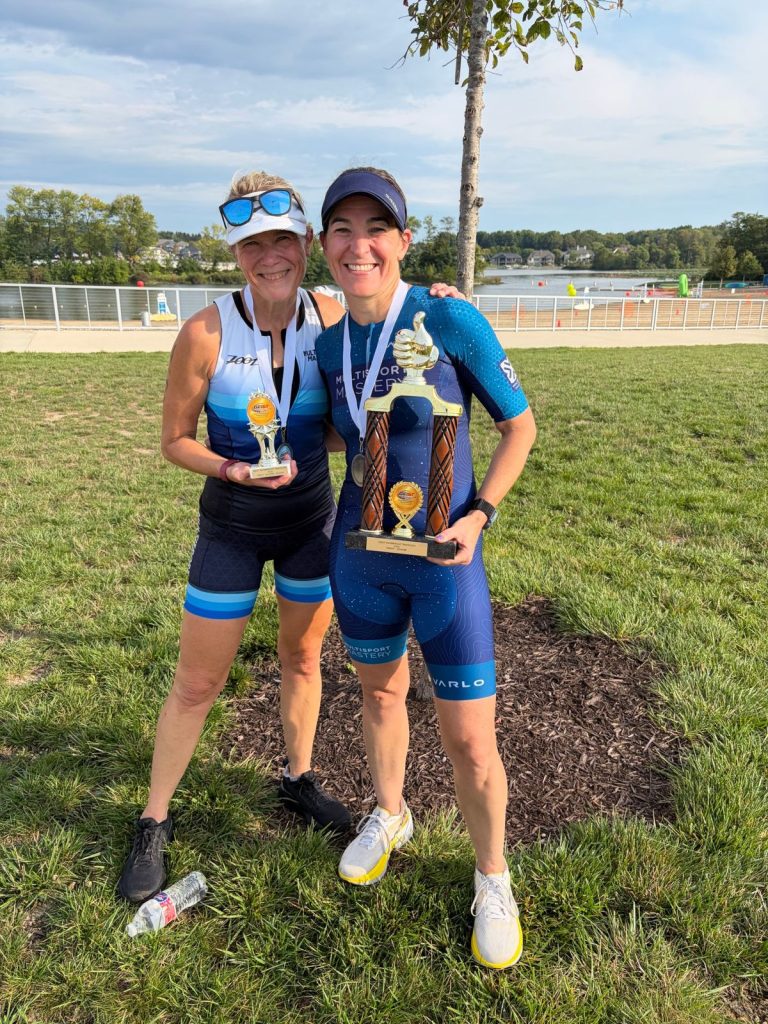 Two Multisport Mastery athletes holding their triathlon trophies