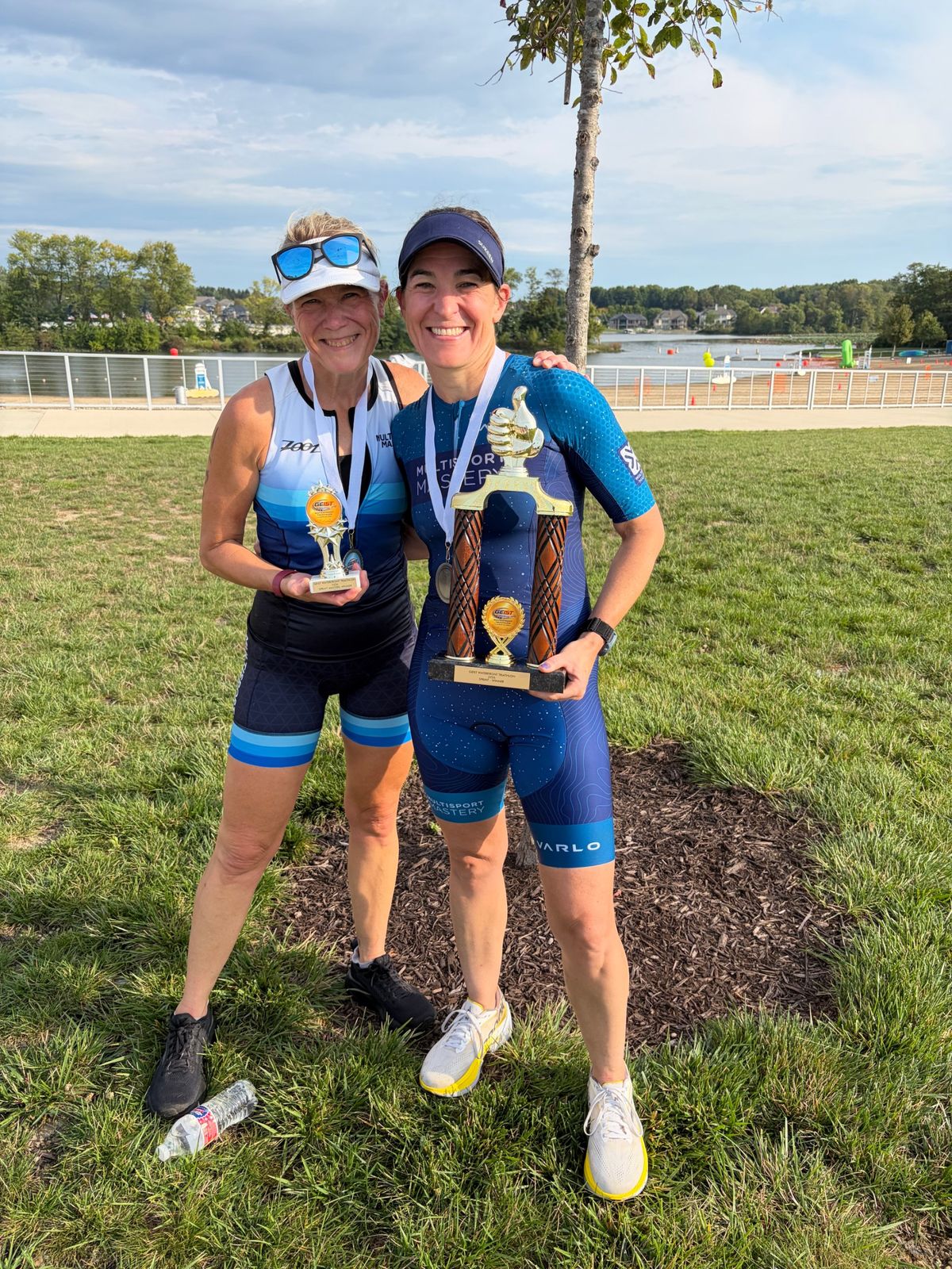 Two Multisport Mastery athletes holding their triathlon trophies