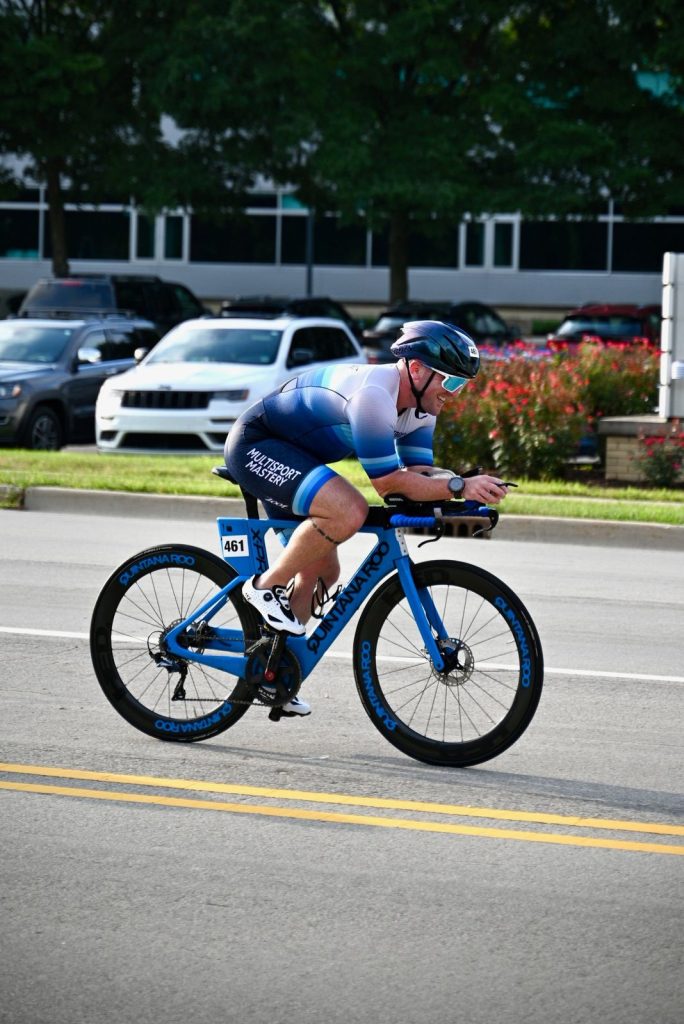 Triathlete in a Multisport Mastery kit riding a blue time trial bike in the aero position