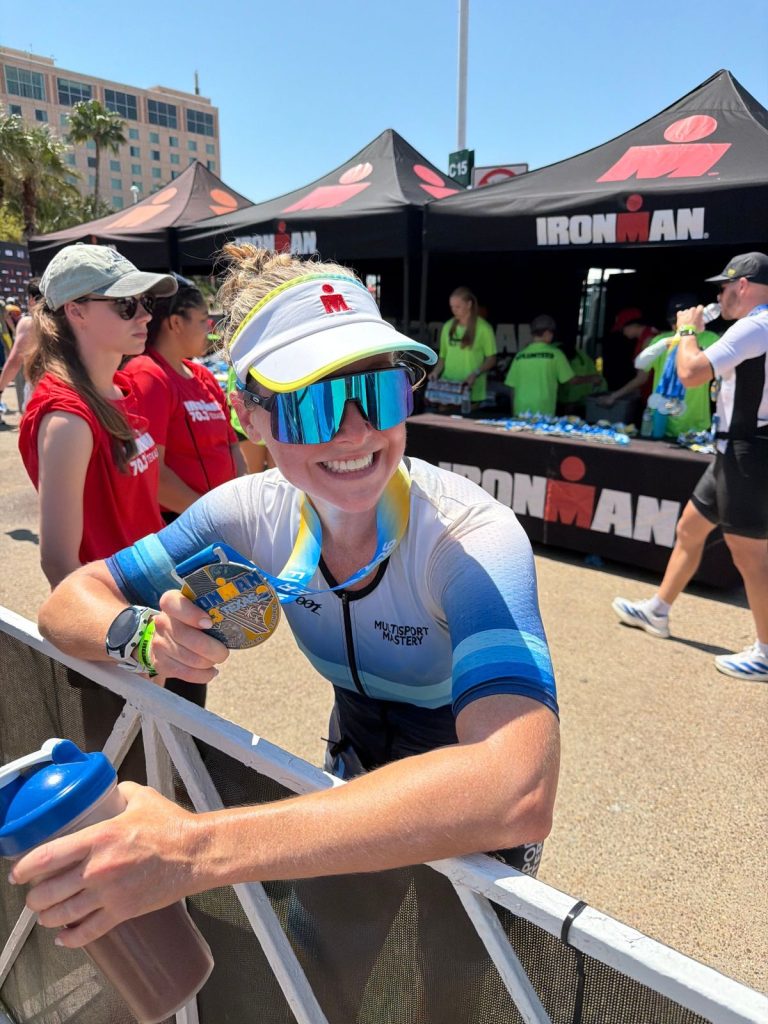 Triathlete smiling with her IRONMAN 70.3 Texas finisher medal