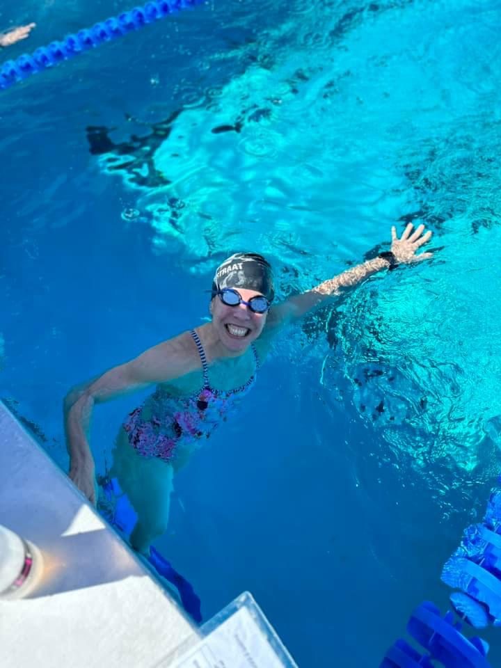 Coach Elizabeth Waterstraat smiling at the pool wall during a swim workout